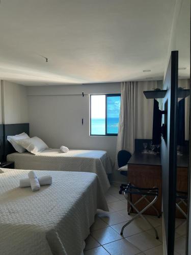 a hotel room with two beds and a window at Apartamento 1307 QUALITY HOTEL in Natal