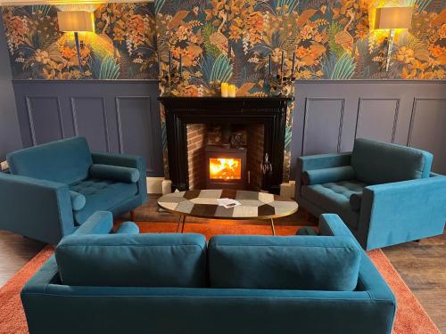 a living room with two blue chairs and a fireplace at Colcombe Castle Hotel in Colyton