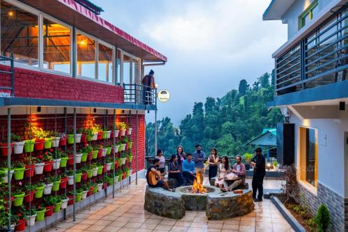a group of people sitting around a fire pit next to a building at PACK Dharamkot in McLeod Ganj