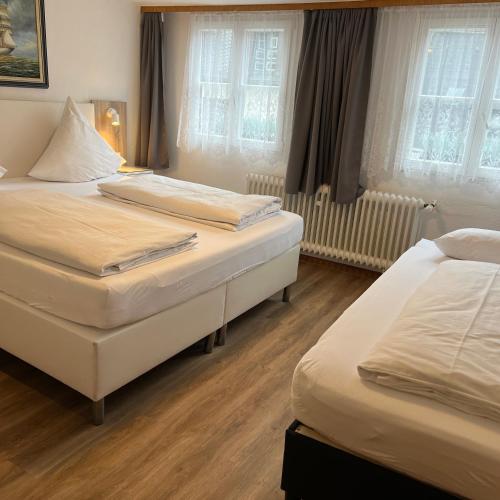 two beds in a hotel room with windows at Eifelerhof hotel Monschau in Monschau