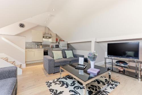 a living room with a couch and a tv at Harrogate Lifestyle Apartments Ltd in Harrogate