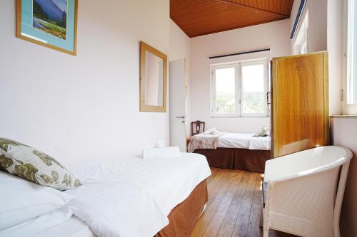 a bedroom with two beds and two windows at casa do campinho in Fundoais