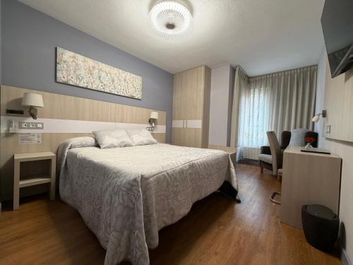 a bedroom with a bed and a couch and a chair at Hotel Bahia in Gijón