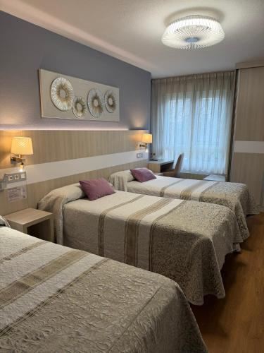 a hotel room with three beds in a room at Hotel Bahia in Gijón