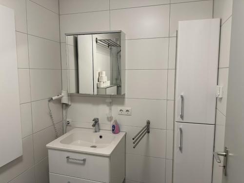 a white bathroom with a sink and a refrigerator at Gästehaus Ludwig in Rust