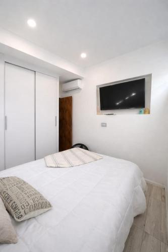 a bedroom with a white bed and a flat screen tv at Brisas paraiso in Concepción del Uruguay