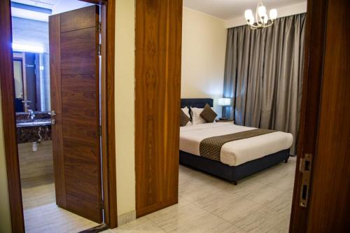 a bedroom with a bed and a door leading to a bathroom at Ginger Luxury House in Juffair