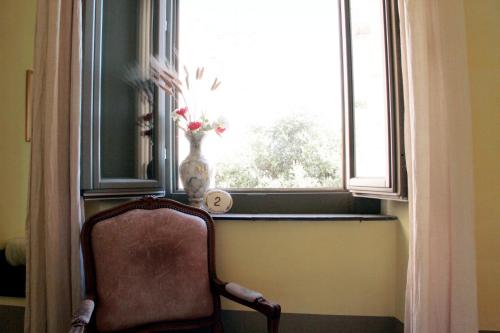 a chair sitting in front of a window with a vase at Locanda Delle Mura Anna De Croy in Magliano in Toscana