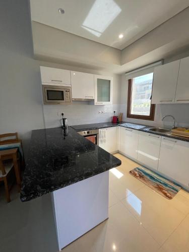 a kitchen with white cabinets and a black counter top at Hakuna Matata Villa - BF 515A in Muscat