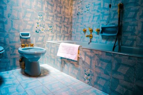 a blue bathroom with a toilet and a bath tub at La casa dei Percy in Varenna