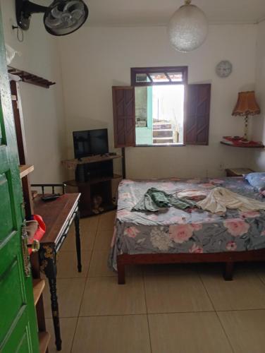 a bedroom with a bed and a table and a window at Casa na cidade ITAPARICA Bahia House in ITAPARICA town in Itaparica