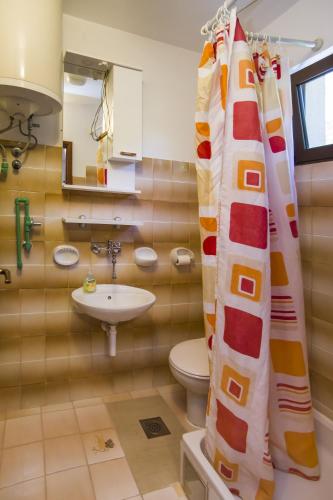 a bathroom with a sink and a toilet and a shower curtain at Robinson Danica 1 in Gornji Dingač