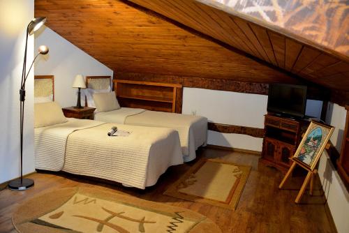 a bedroom with two beds and a television in a attic at Momini Dvori Boutique Guest House in Bansko