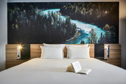 a bedroom with a large bed with a book on it at Novotel Massy Palaiseau in Palaiseau