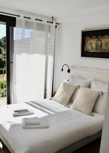 uma cama branca com travesseiros brancos e uma janela em My St-Tropez em Saint-Tropez