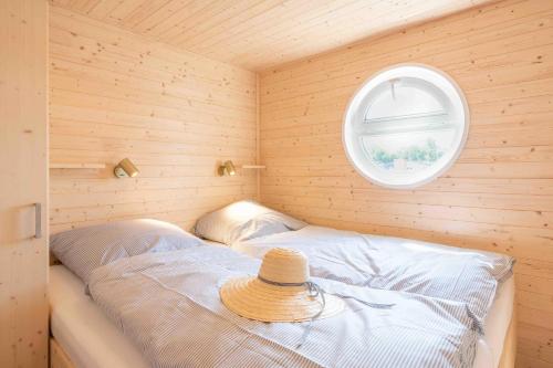 a small room with a bed with a hat on it at Hausboot Sunshine Heiligenhafen in Viehhof