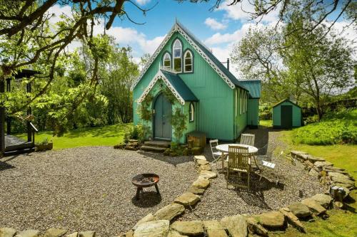 a green house with a table and chairs in front of it at The Tabernacle, Design-led Converted Chapel with Hot Tub, Highland Perthshire in Aberfeldy