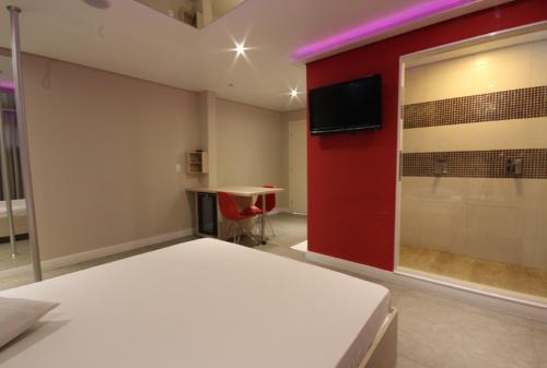 a room with a bed and a tv on a red wall at Flow Motel (Adult Only) in Valinhos