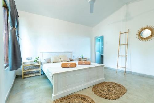 a white bedroom with a bed and a ladder at Naïa Ocean House Midigama in Midigama West
