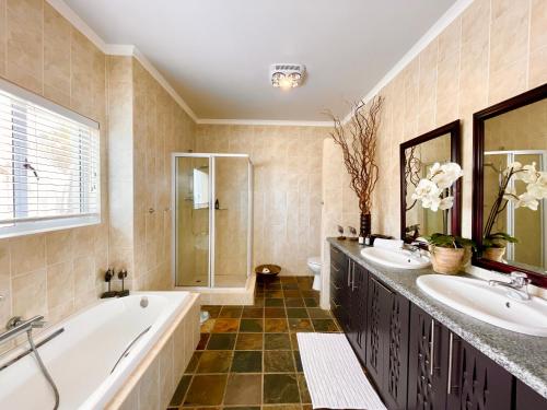 a bathroom with two sinks and a tub and a shower at Pebble Beach Seafront Condo in Swakopmund