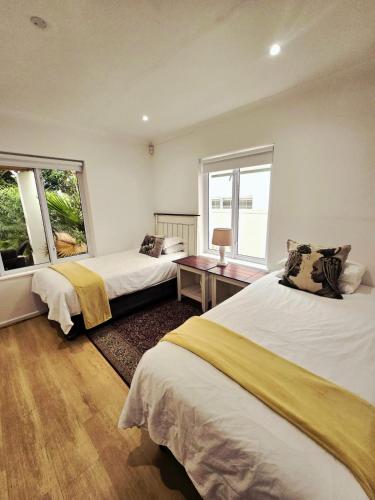 a bedroom with two beds and a desk and two windows at Art House in Stellenbosch