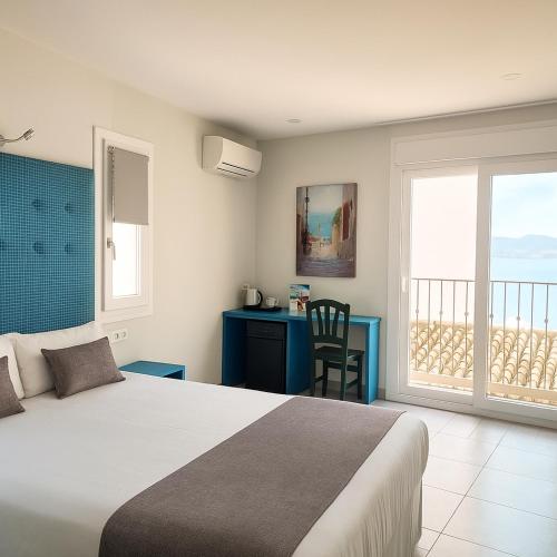 a bedroom with a bed and a view of the ocean at Hotel Clopy Rocamar in Benidorm