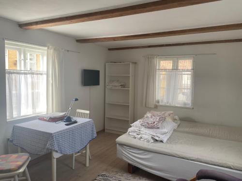 a bedroom with a bed and a table and windows at City gæstehus kerteminde in Kerteminde