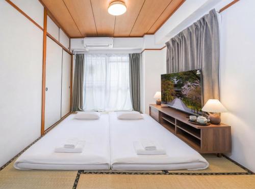 a bedroom with a large bed and a tv at Home Stroy in Tokyo - 1970 Hotel- 江東区門前仲町 2min walk- 東京屋語 in Tokyo