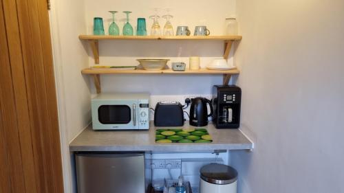 a kitchen with a counter with a microwave and a coffee maker at The Stoat House in St. Leonards