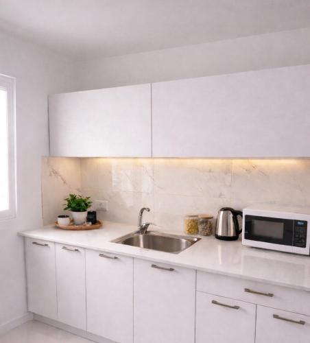 a white kitchen with a sink and a microwave at Romy secrets in Netanya