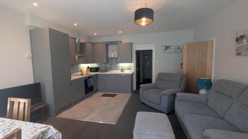 a living room with two couches and a kitchen at Buile Hill Holiday Flats in Llandudno