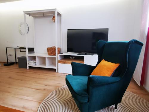 a living room with a blue chair with an orange pillow at Gemütliches Souterrain in Langenargen in Langenargen