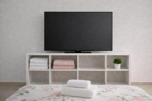 a tv sitting on top of a white shelf with towels at R suite delux in Netanya