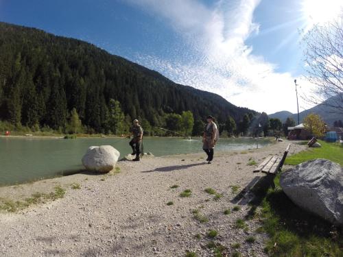 two men walking along a river with a bench at Sarca Lodge Val Rendena in Dare