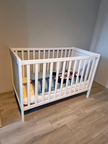 a white crib in a room with a wooden floor at Up de platse in Lo-Reninge