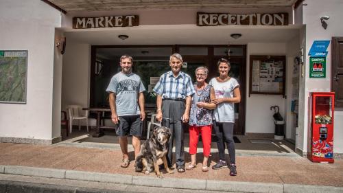a group of people and a dog in front of a store at Sarca Lodge Val Rendena in Dare