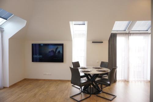 a dining room with a table and a tv on the wall at Modern New-Build Apt, managed by RentiFor in Klaipėda