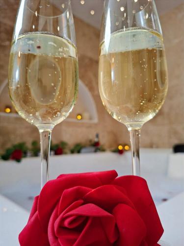 two glasses of wine and a red rose on a table at La Suite Balinaise in Quimper