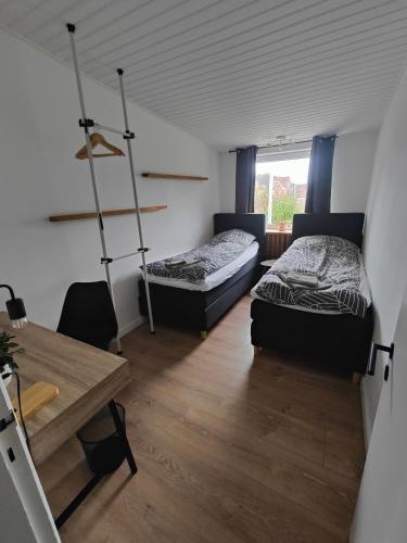 two beds in a room with a desk and a table at Felicia's Apartments in Hovborg