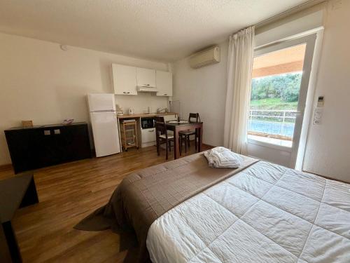 a bedroom with a bed and a table and a kitchen at SAINT-FLORENT Studio PISCINE FLO300-146 in Saint-Florent
