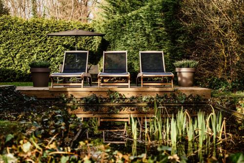 three chairs sitting on a wooden deck with an umbrella at Privesauna Huisje 33 in Ermelo