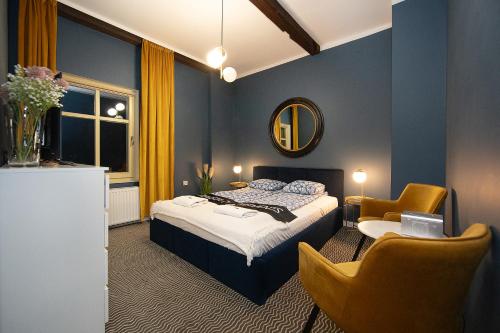 a bedroom with a bed and two chairs and a mirror at CIENISTA 7 APARTMENTS in Lądek-Zdrój