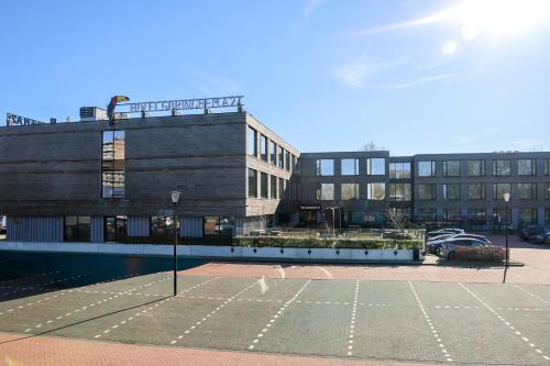 a parking lot with a tennis court in front of a building at Van der Valk Hotel Gorinchem-A27 in Gorinchem