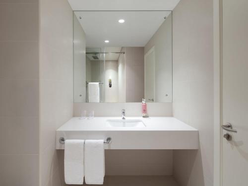 a white bathroom with a sink and a mirror at Rove Dubai Marina in Dubai