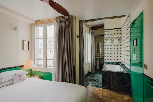 a bedroom with a bed and a bathroom with a tub at Hôtel Grand Amour in Paris