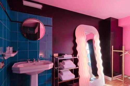 a bathroom with a sink and a tv on the wall at Hôtel Grand Amour in Paris