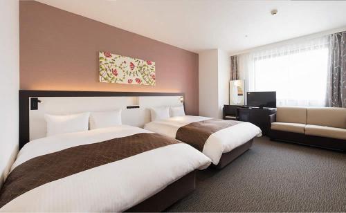 a hotel room with two beds and a couch at Osaka Airterminal Hotel in Toyonaka