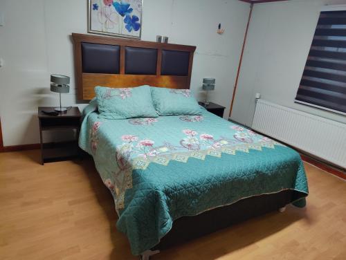 a bedroom with a bed with a green comforter at Casa amoblada en Punta arenas in Punta Arenas