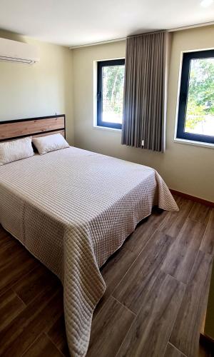a bedroom with a large bed and two windows at Quinta da Toqueira in Canedo