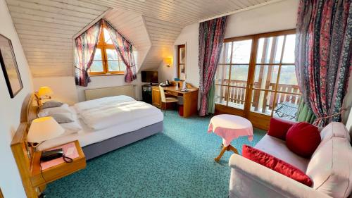 a bedroom with a bed and a desk and a couch at Hotel und Gutsgaststätte Rappenhof in Weinsberg